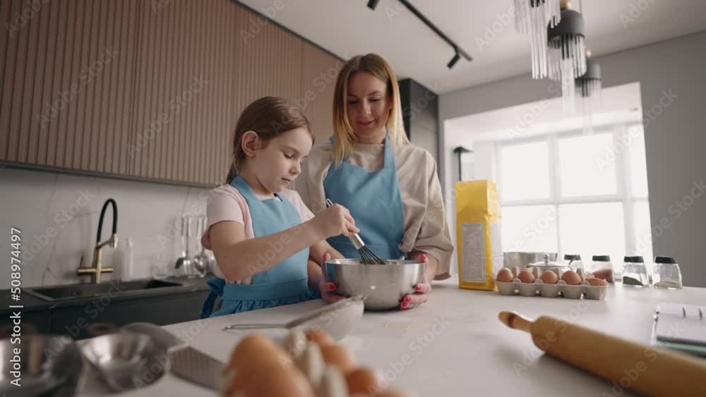 woman and her little helper are cooking together in home, little daughter and mother are making cake woman and her little helper are cooking together in home, little daughter and mother are making cake
