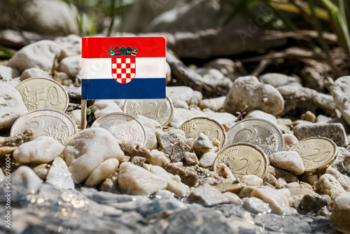 Fototapeta Naklejka Na Ścianę i Meble -  Croatia flag with euro coins amid gravel surface on the riverbank,currency exchange,business finance and economy concept,macro close-up