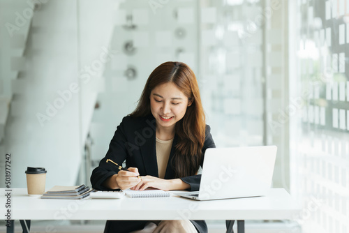 Young beautiful woman using her laptop while sitting in a chair at her working place, Small business owner people employee freelance online sme marketing e-commerce telemarketing concept.