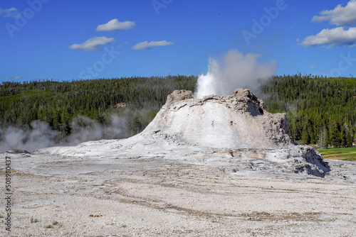 Small geyser erupting in the Old Faithful geyser area in the Yellowstone National Park, Wyoming, USA. Geothermal activity in volcanic landscape.
