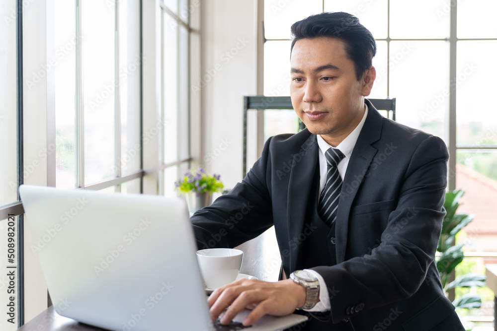 Adult Asian business man typing and working with laptop computer at the workspace office. Adult Asian business man typing and working with laptop computer at the workspace office.