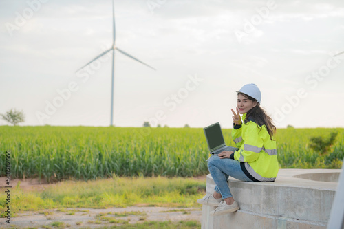 women engineer working and holding the report at wind turbine farm Power Generator Station on mountain,Thailand people