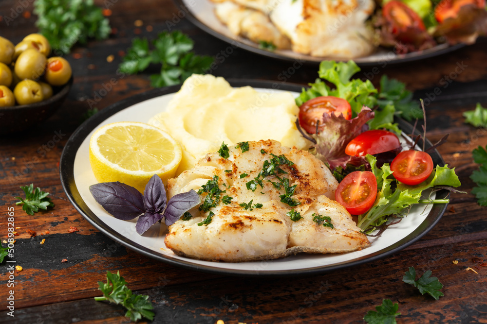 Fried cod loin fillet with mashed potato and vegetable salad served with fresh lemon Fried cod loin fillet with mashed potato and vegetable salad served with fresh lemon