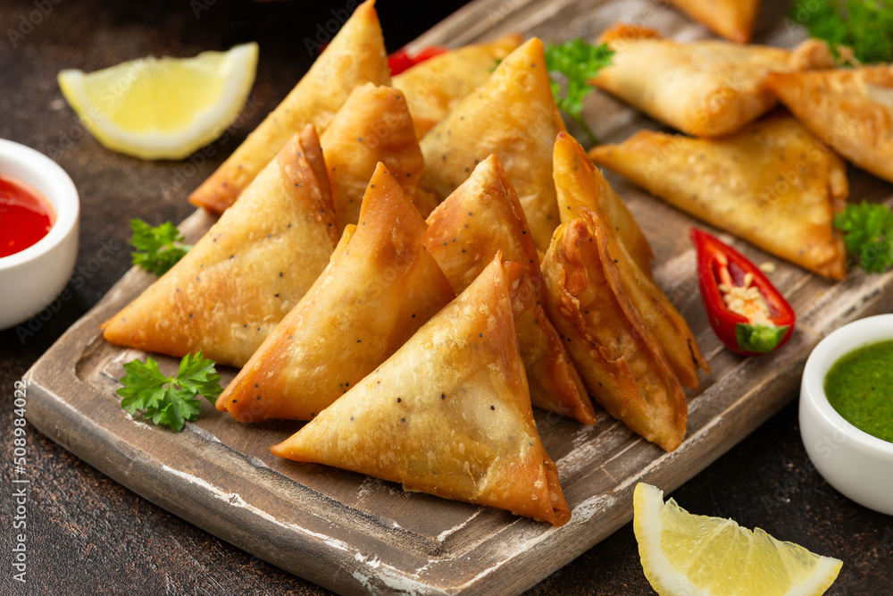 Fried samosas with vegetable filling, popular Indian snacks on wooden board Fried samosas with vegetable filling, popular Indian snacks on wooden board