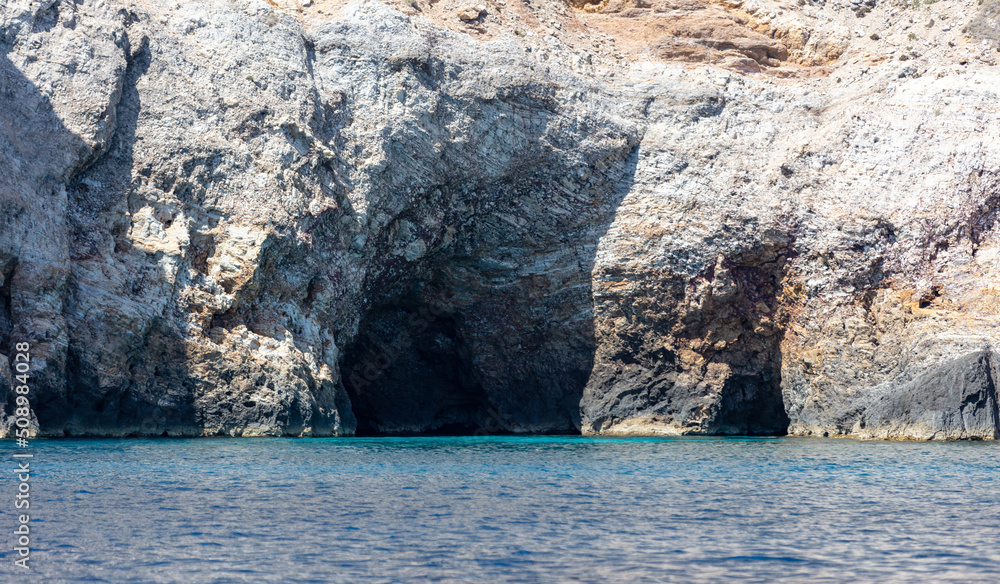 Cave and cliff, Aegean Sea. Cyclades Greece. Rock coast, turquoise water. Seascape near Ios island