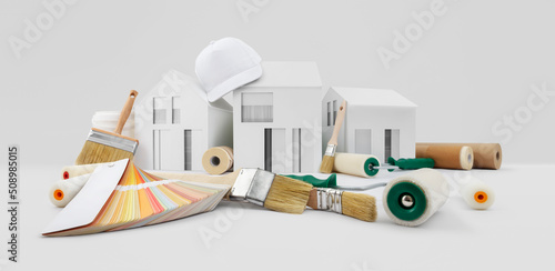Papier peint house painter tools, brushes, paint rollers, paper masking tape and colors swatches on desk with model house, supply and service in color shop in the hardware and store of building material