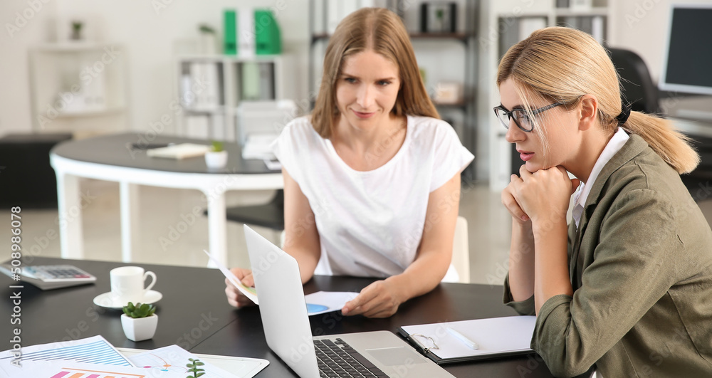 Beautiful businesswoman and her colleague discussing issue at workplace Beautiful businesswoman and her colleague discussing issue at workplace