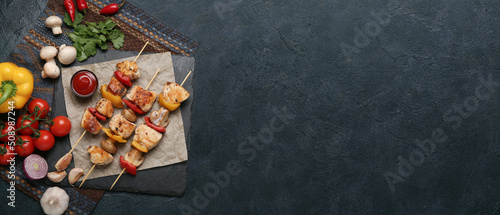 Grilled chicken skewers with vegetables and sauce on black background with space for text, top view