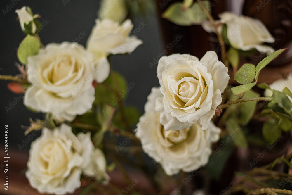 A bouquet of white yellow cream-coloured artificial roses on long stems in close-up.