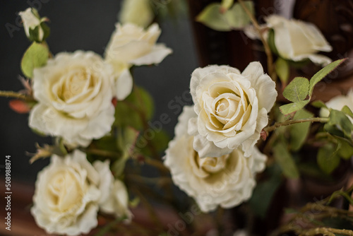 A bouquet of white yellow cream-coloured artificial roses on long stems in close-up.