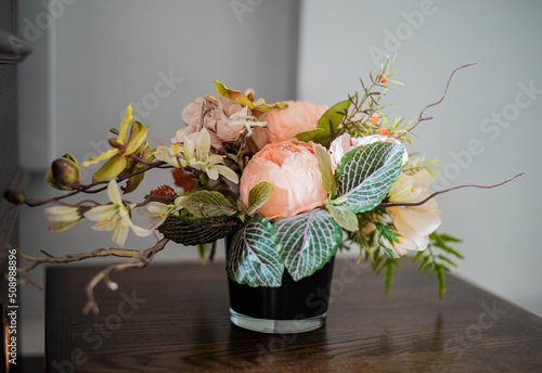 A composition of artificial flowers in a vase on a table.