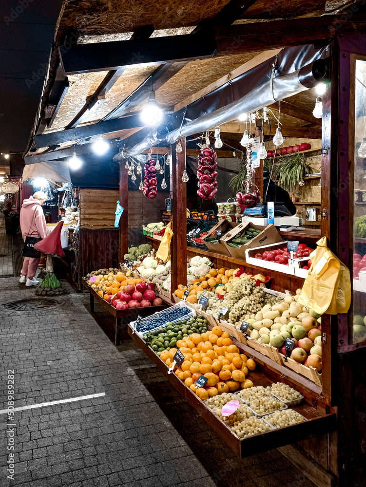 Night walk through the shopping district under street lamp, among the fruit stalls