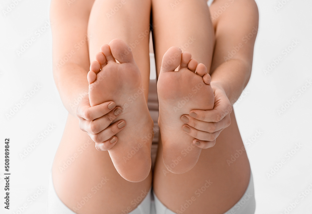 Young woman making foot massage on light background, closeup Young woman making foot massage on light background, closeup