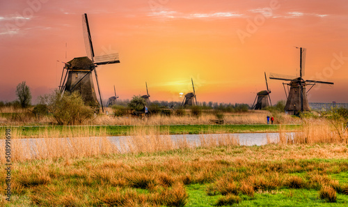 Two tourists hiking through the many working windmills at Kinderdijk in the Netherlands photo