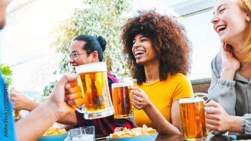 Fotografiet Happy multiracial friends cheering beer glasses at brewery pub - Group of young