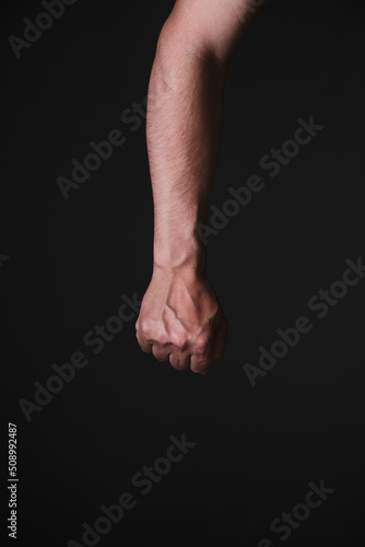 Brutal mans hand with protruding veins, black background.
