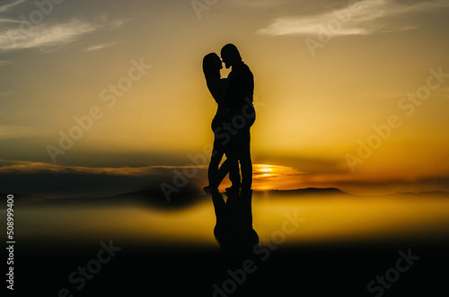 Vászonkép silhouette of a loving couple embracing at sunset