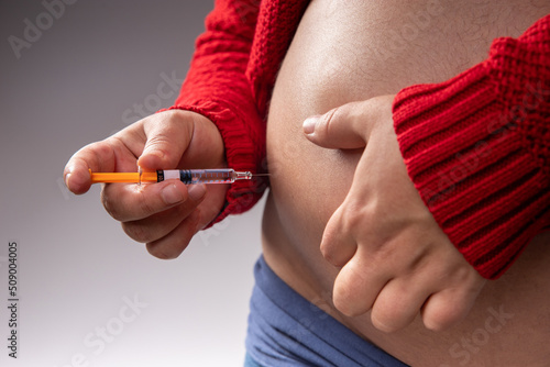 Billede på lærred A pregnant woman injects herself a blood thinner with a syringe into her belly to prevent blood clots during pregnancy