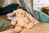 Soft toy bunny on bed with pillows and baldachin in bedroom