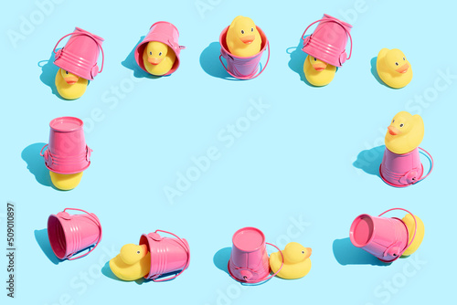Obraz na plátně Yellow rubber ducky and pink bucket in different funny poses on pastel blue backround
