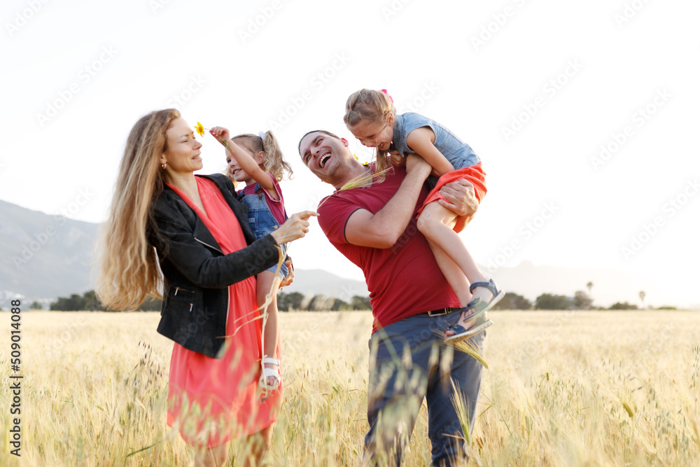 Happy family father of mother and two daughters sisters on nature at sunset.Carefree parents having fun with their kids on a field. Happy family father of mother and two daughters sisters on nature at sunset.Carefree parents having fun with their kids on a field.