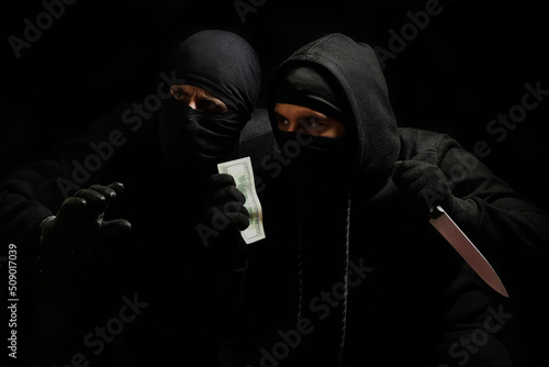 Wallpaper Mural thieves in black masks with a knife and dollars in their hands on a black background