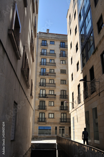 Rua estreita de cidade com prédios altos e uma pessoa em movimento, Vigo, Espanha 