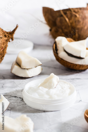 A piece of coconut in coconut oil in a jar and coconut. Natural cosmetic. Vertical view