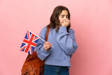 Little girl holding an United Kingdom flag isolated on pink background having doubts