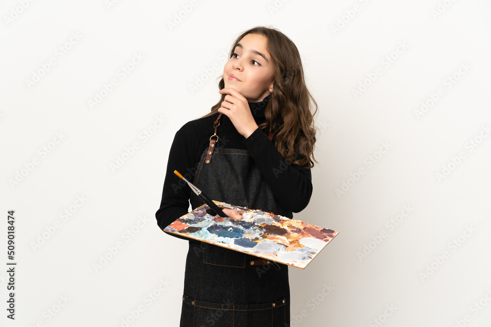 Little artist girl holding a palette isolated on white background and looking up Little artist girl holding a palette isolated on white background and looking up