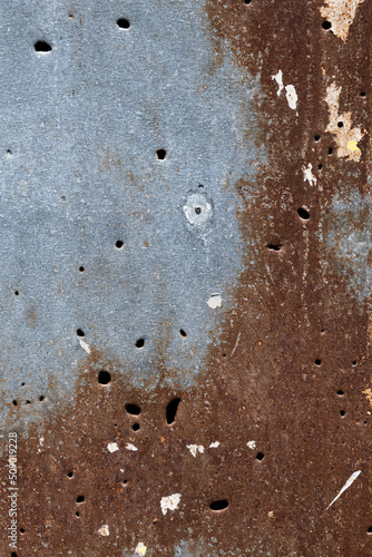 Holes from gunshots and shrapnel on a rusty metal wall in the war zone in Ukraine. photo