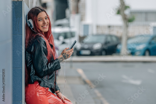 redhead girl smiling happy with mobile phone and earphones on the street © carballo