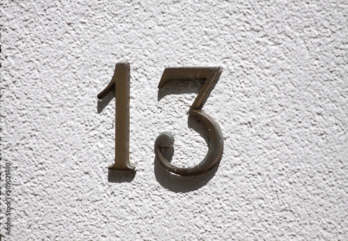 House number 13 sign on a white stone wall