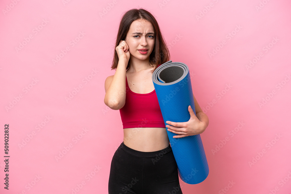 Young sport Ukrainian woman going to yoga classes while holding a mat isolated on pink background frustrated and covering ears Young sport Ukrainian woman going to yoga classes while holding a mat isolated on pink background frustrated and covering ears