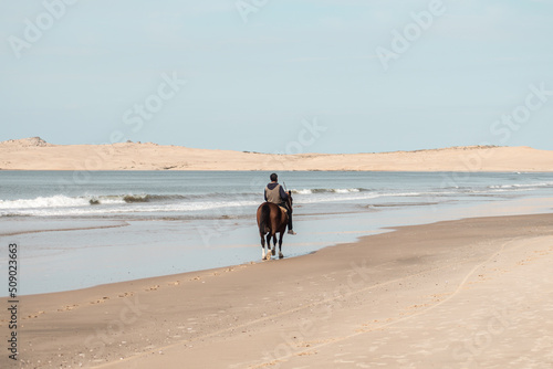 Person on horseback on the beach of Barra de Valizas with the dunes in the background