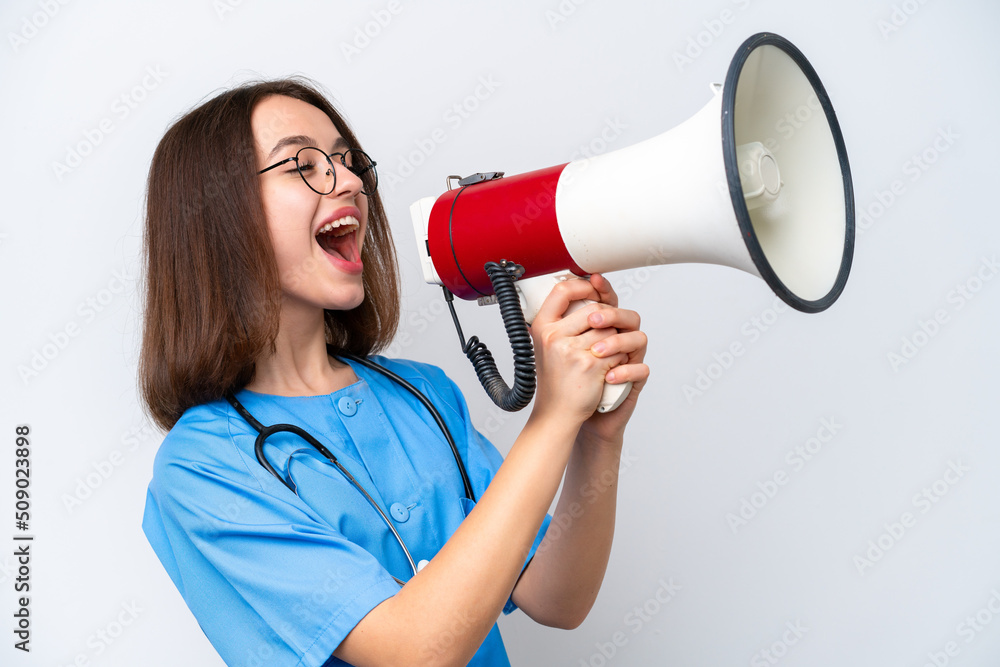 Young nurse Ukrainian woman isolated on white background shouting through a megaphone Young nurse Ukrainian woman isolated on white background shouting through a megaphone