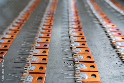 A frameless transistor for amplifying the current with a chip soldered onto a hand-made copper radiator lies in rows in a cassette for sealing. photo