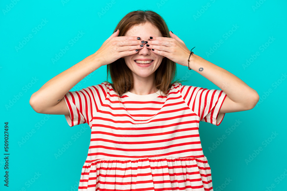 Young English woman isolated on blue background covering eyes by hands and smiling Young English woman isolated on blue background covering eyes by hands and smiling