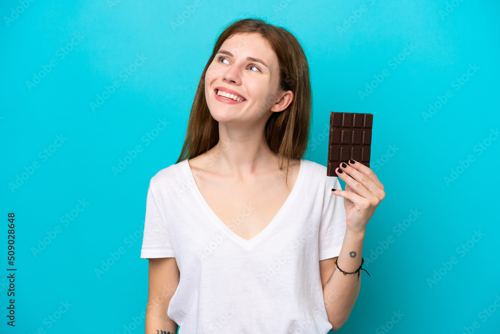 Young English woman with chocolat isolated on blue background thinking an idea while looking up