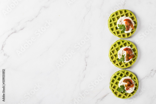 Round Spinach waffles with cottage cheese, cherry tomatoes and parsley. Top view. Copy space © Aksana