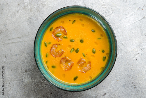 Pumpkin cream soup with shrimp and pumpkin seeds on grey table top view