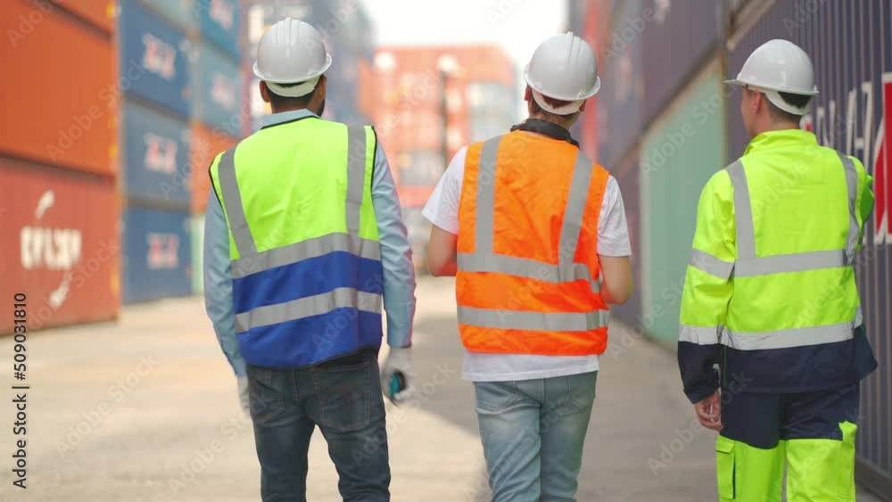Back of three of cargo container worker as foreman or technician with multiethnic discuss together during walk in workplace area. Back of three of cargo container worker as foreman or technician with multiethnic discuss together during walk in workplace area.