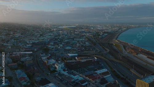 Forwards fly above city at dusk. Railway tracks and roads leading along sea coast. Port Elisabeth, South Africa