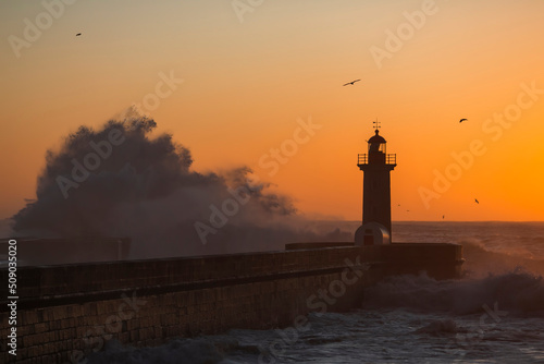 View of the Lighthouse with huge wave during sunset at Atlantic ocean, Porto, Portugal.