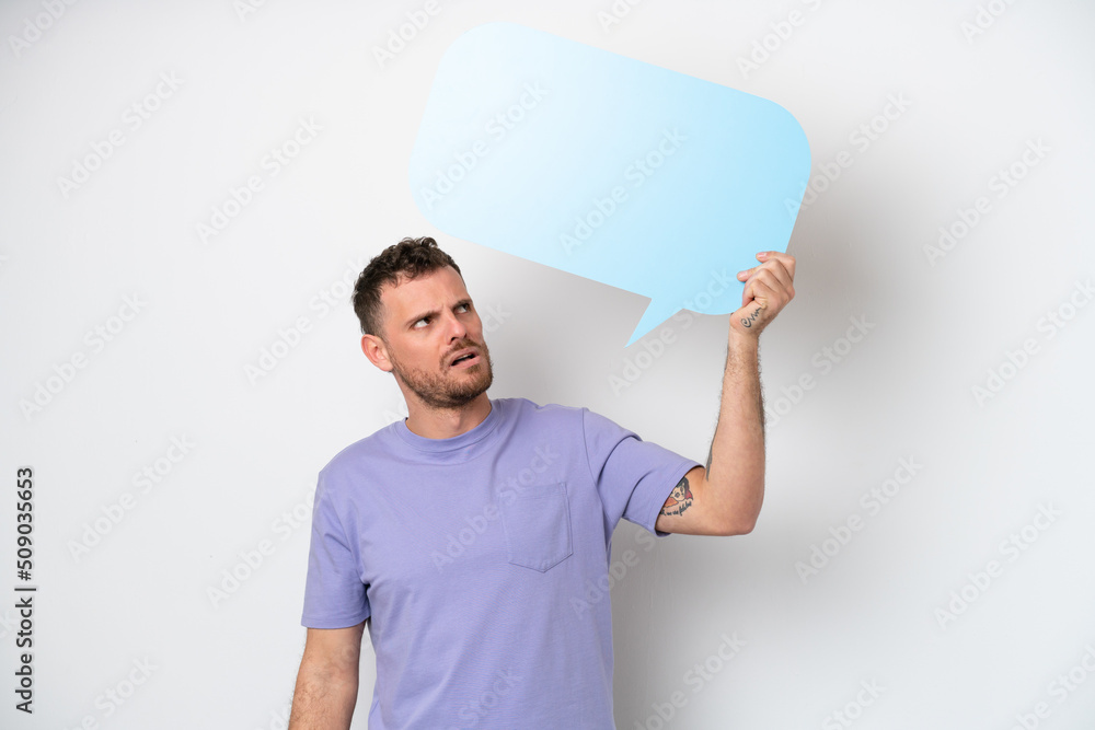 Young Brazilian man isolated on white background holding an empty speech bubble and with sad expression Young Brazilian man isolated on white background holding an empty speech bubble and with sad expression