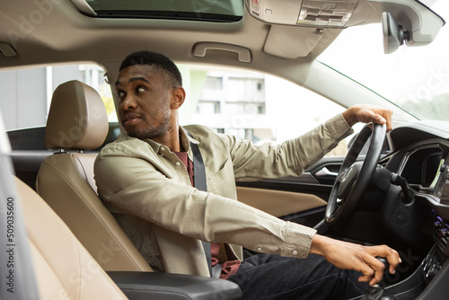 African American male driver looks back and parks the car
