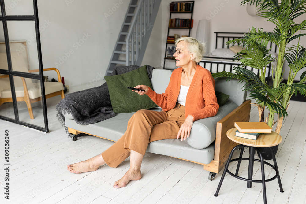 Beautiful senior woman with short grey hair and lovely smile watching television at home. Concept of attractive good looking elderly female, mature women with active lifestyle. Look healthy Beautiful senior woman with short grey hair and lovely smile watching television at home. Concept of attractive good looking elderly female, mature women with active lifestyle. Look healthy