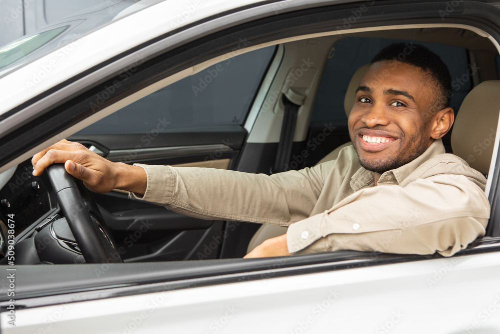 Handsome black man driving his car and smiling at the camera
