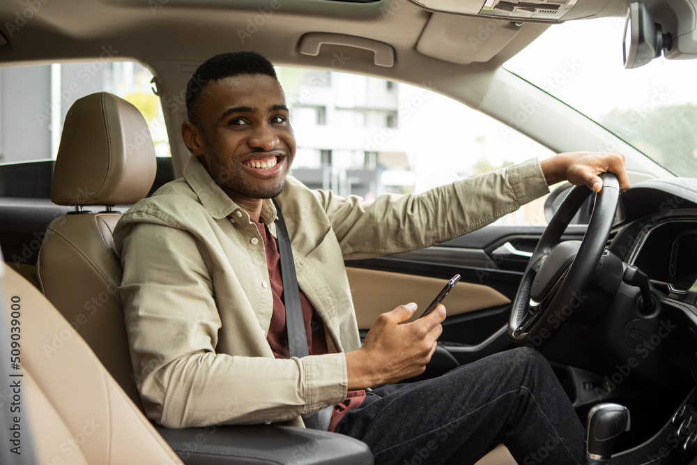 Handsome young man with smartphone near modern car outdoors Handsome young man with smartphone near modern car outdoors