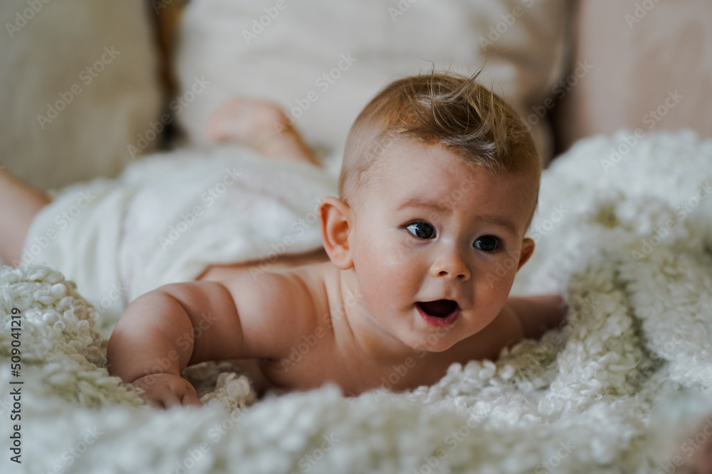 adorable naked 6 month old baby boy lying on belly and looking up in